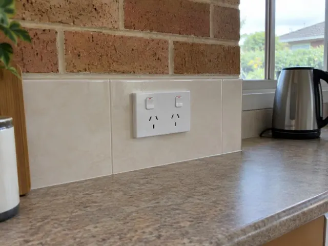 White double power point on a tiled kitchen splashback above a benchtop in a brick home in Tuggerah